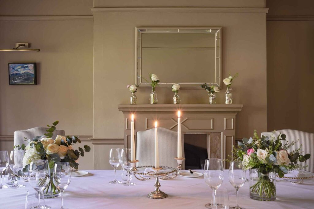 detailed shot of a wedding dinner table featuring candles, flowers and glassware