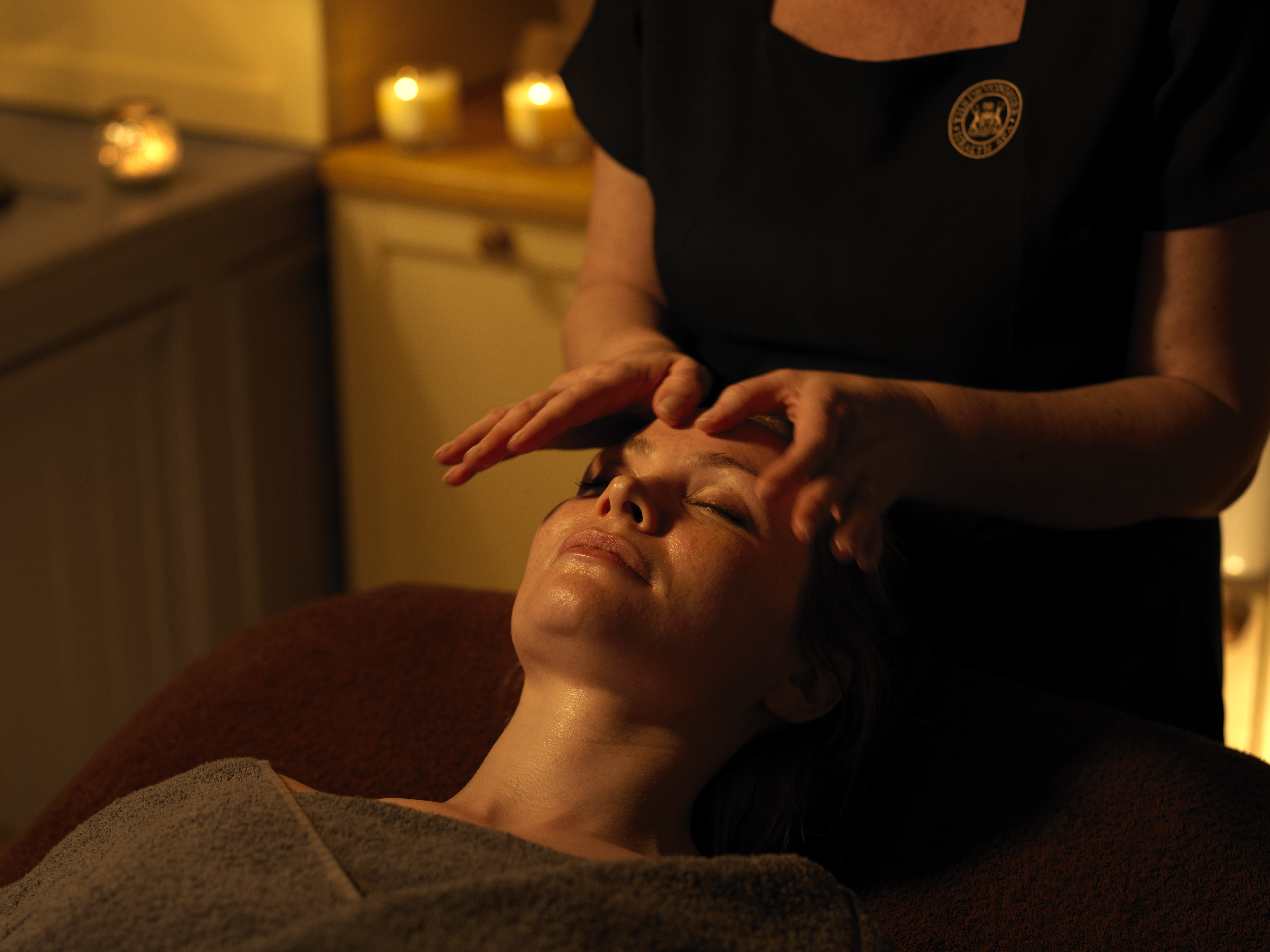 A massage is taking place with candles in the background.