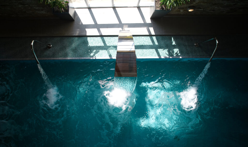 The spa pool with the bubbling water jets and the traditional stone wall behind.