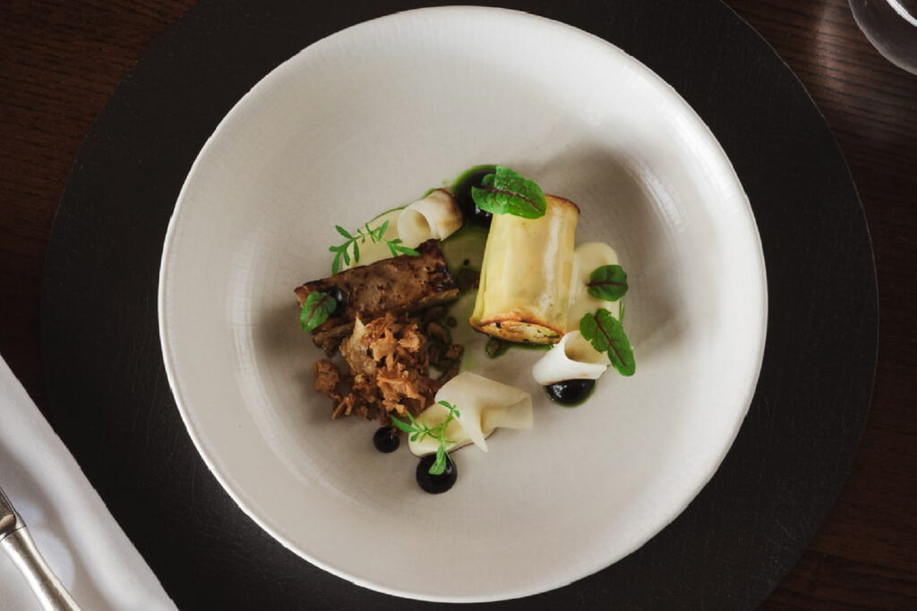 A dish is on a black table with colourful vegetables.