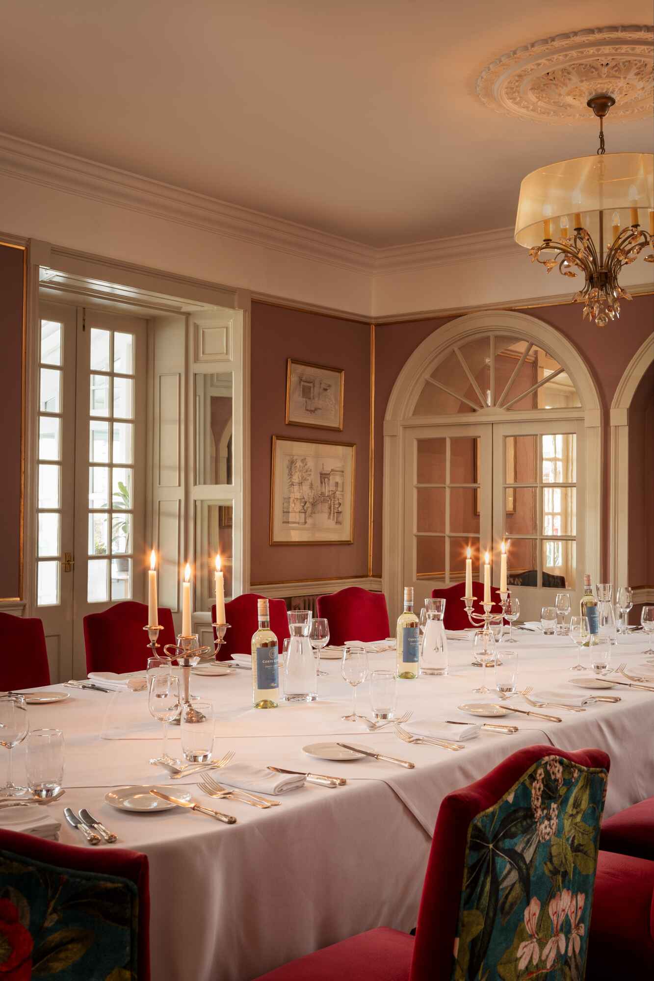 Private dinner room with pink walls and chairs with large arched windows