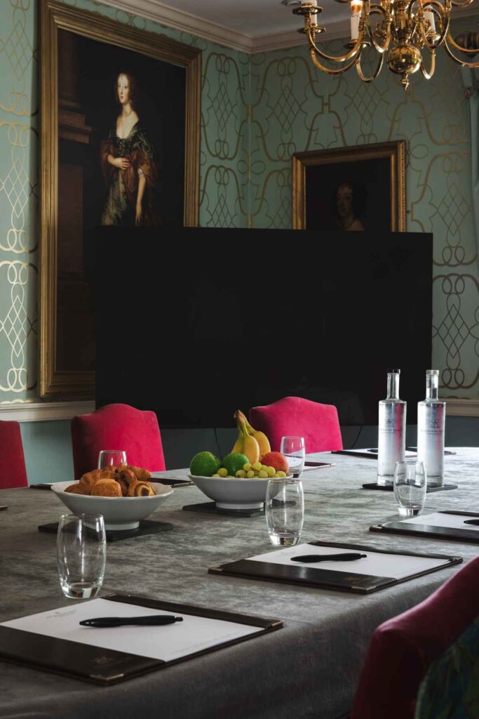 Darker meeting room detailing pink chairs and fruit on the table