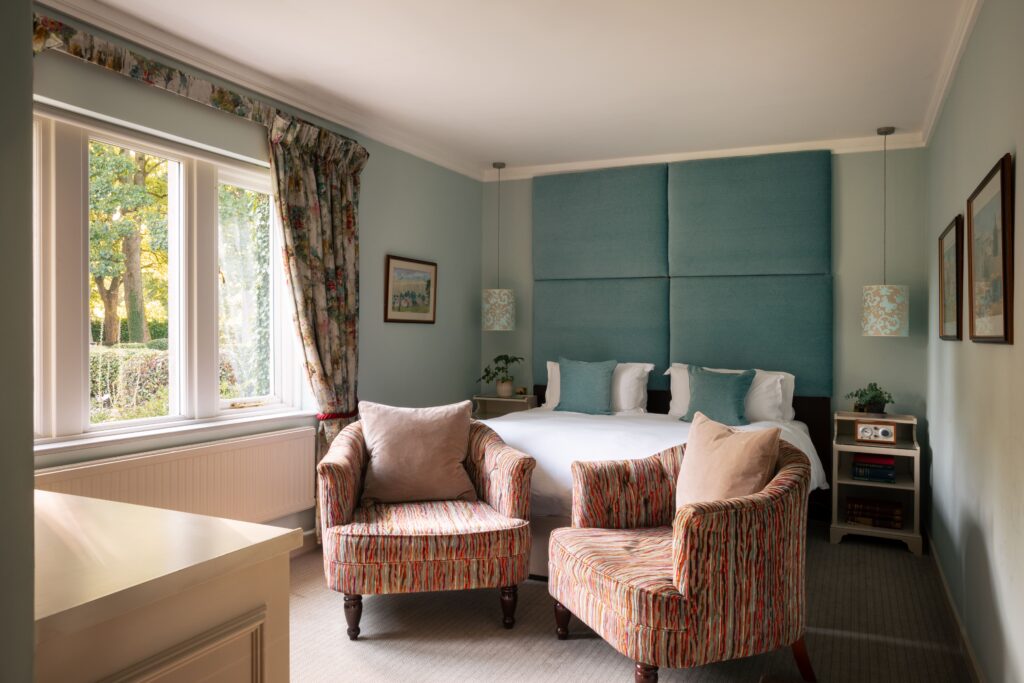 A blue bedroom with large blue headboard and hanging ceiling lights.