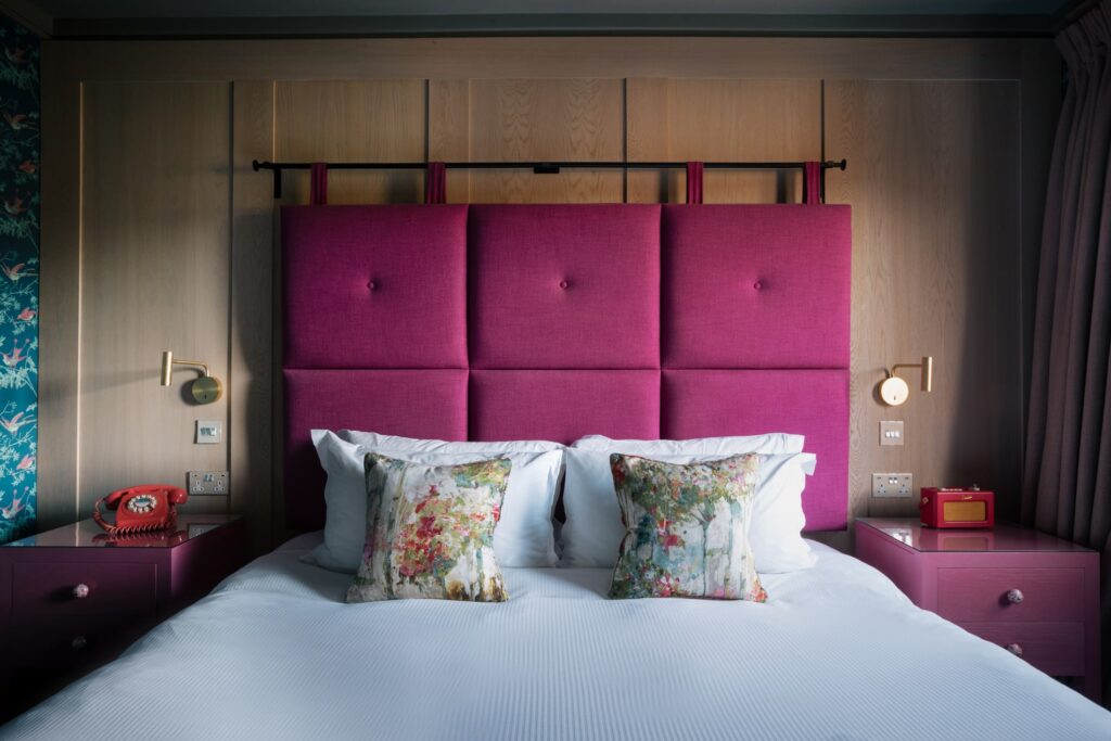 A bedroom with wooden panelling and a pink headboard.