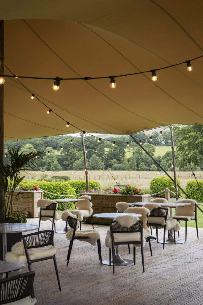 Large outdoor terrace and dining area, with comfy chairs and views over the rolling hills.