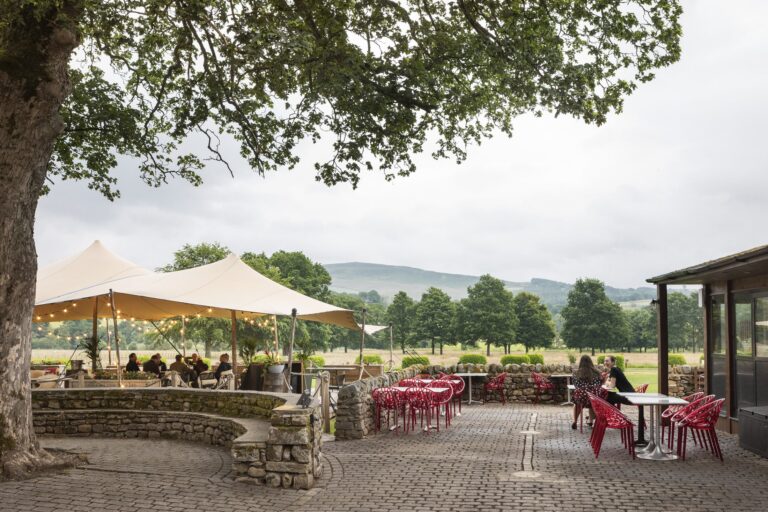 Large outdoor terrace and dining area, with comfy chairs and views over the rolling hills, with the summer flowers in bloom around.
