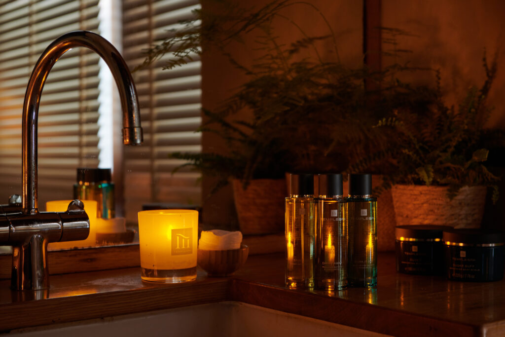 A peaceful spa treatment room with candles and mood lights and products and plants.