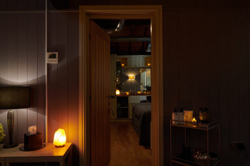 A peaceful spa treatment room with candles and mood lights and products and plants.