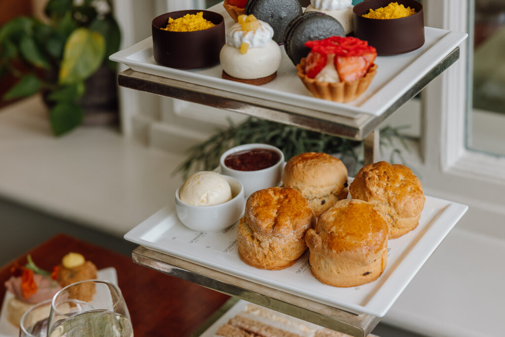 A luxurious afternoon tea stand in The Garden Room filled with sandwiches, sweet treats and scones.